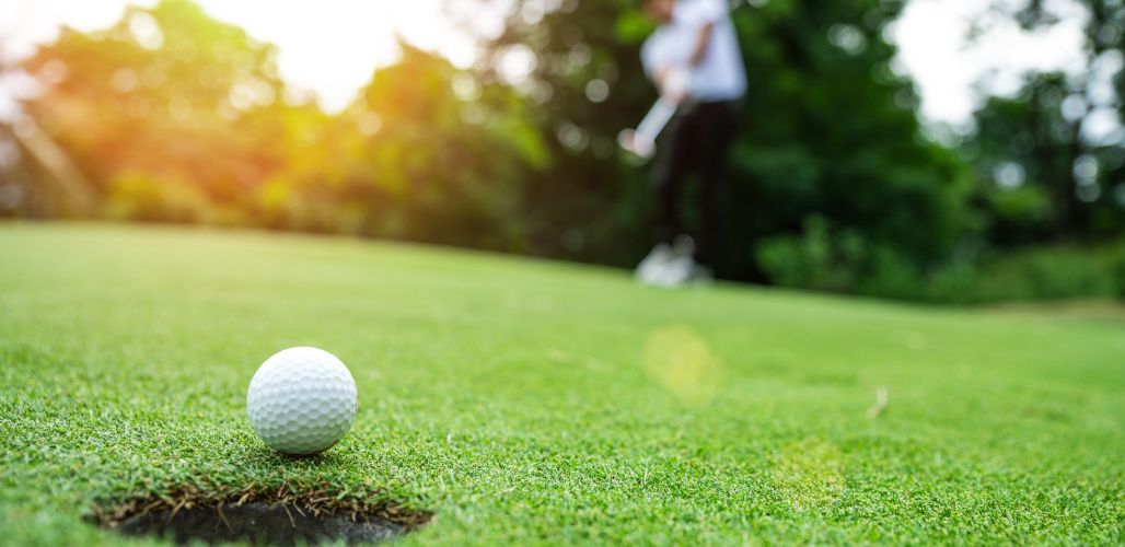Close up golf ball on green grass field by Pakorn